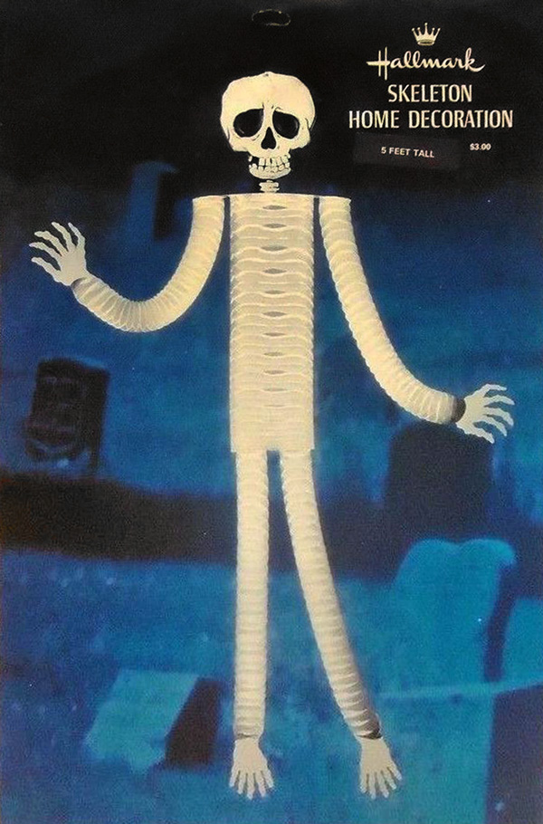 Spooky front image of package by Hallmark is a honeycomb Skeleton Home Decoration (1970's) in front of a dark blue graveyard photo - shown here to develop research for The Halloween Retrospect, Volume 3 - a new guidebook series for collectors.